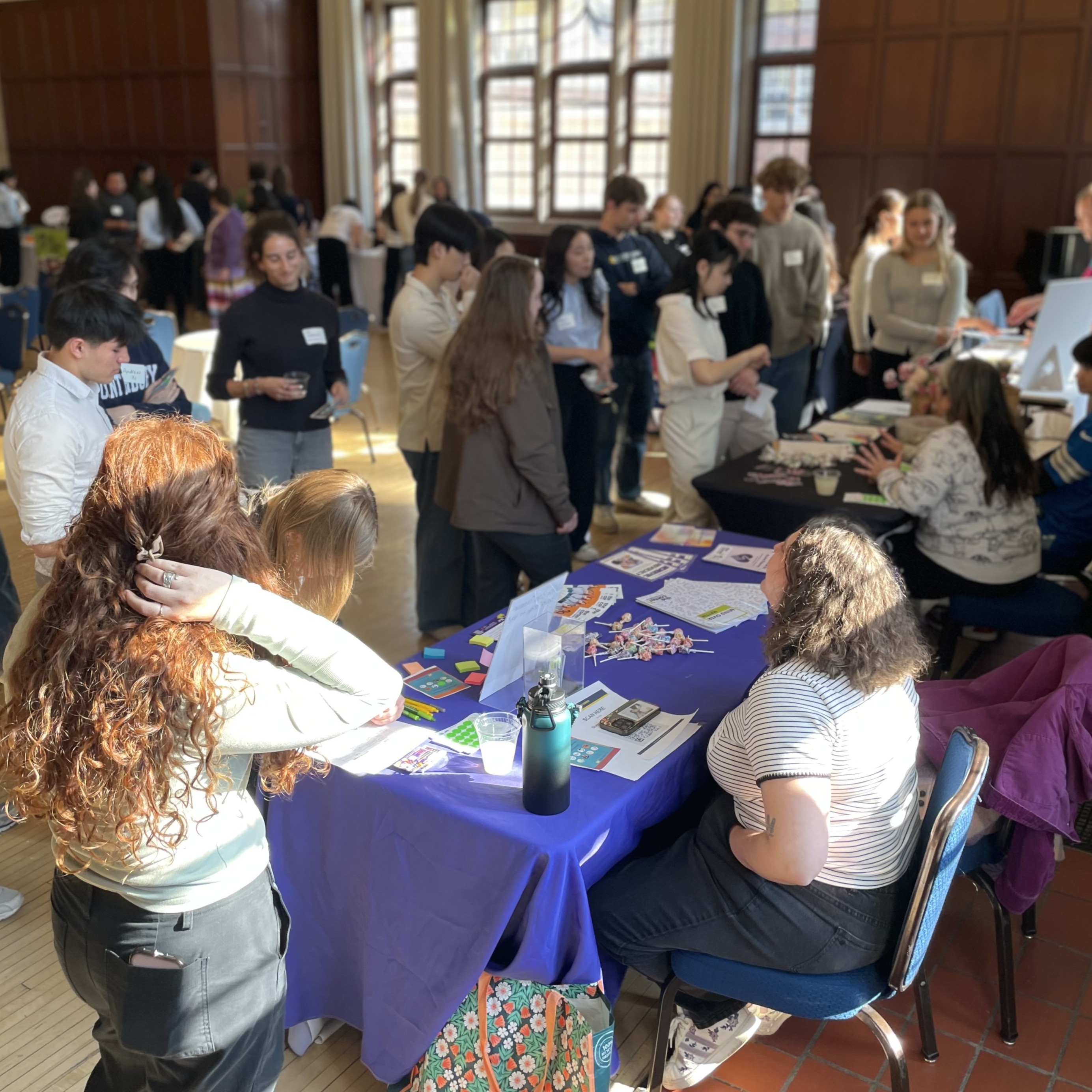 Students gathered around tables with table skirts in Union ballroom to sign up for volunteer opportunities with community partners