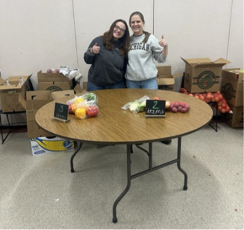 Two volunteers standing in front of food pantry