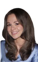 A head-and-shoulders picture of a woman with long brown hair. She is wearing a periwinkle shirt and smiling.