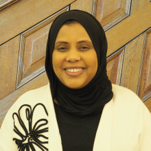 headshot of Hawa Haji-Hassan in front of wood paneled wall