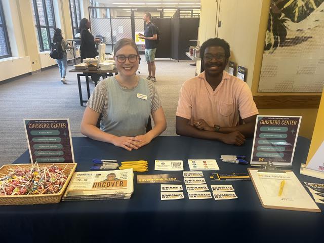 Two people sitting behind a sign-up table.