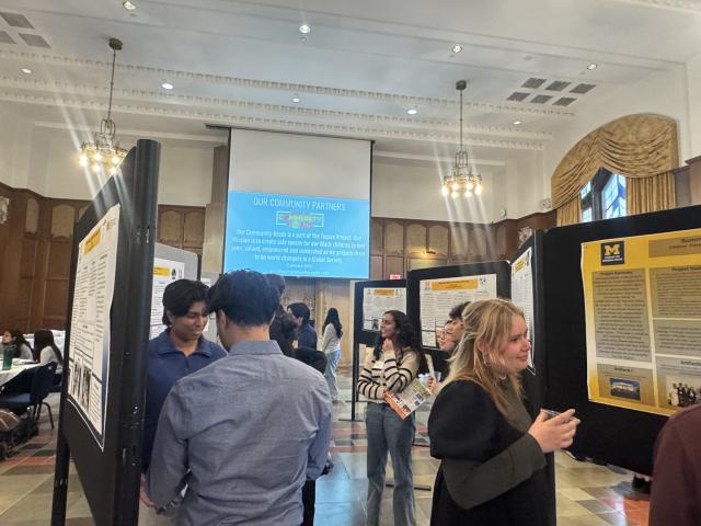 A group of students looking at a board of posters.