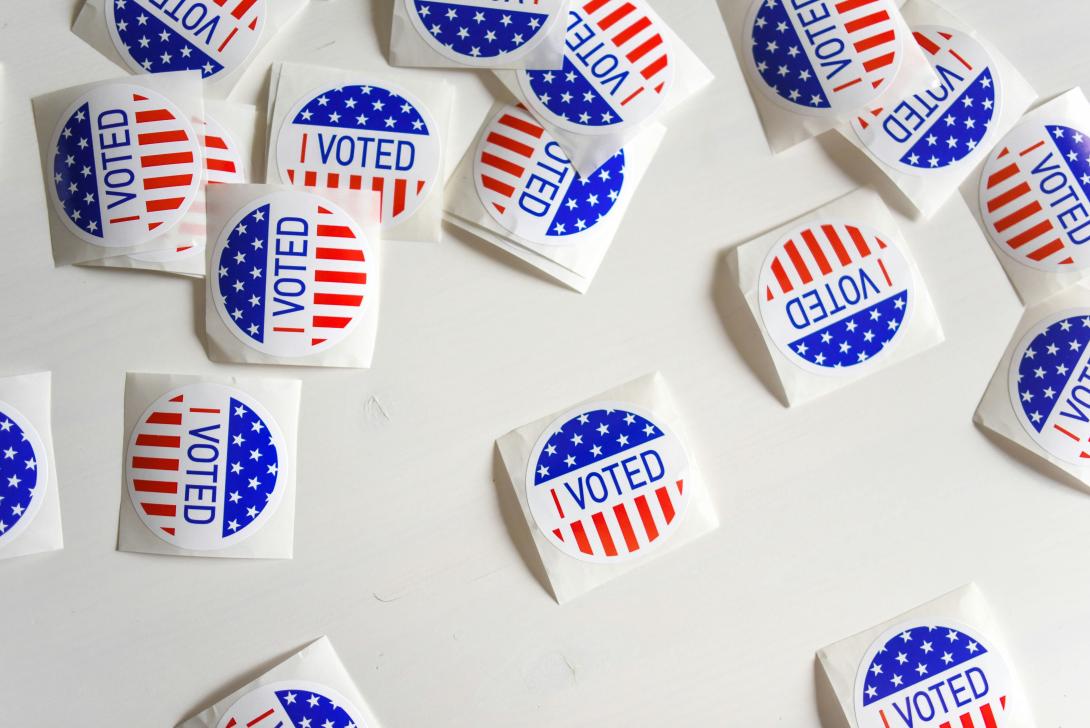 Red, white, and blue stickers that read "I voted" scattered on a white background.